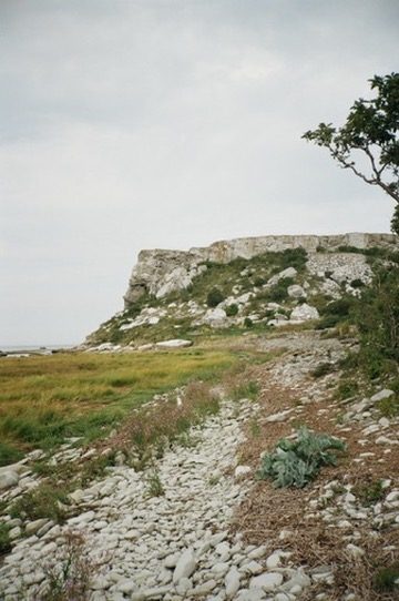 A limestone cliff above a stony shore