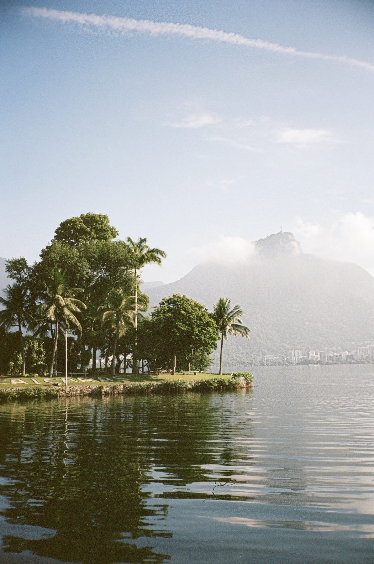 Palms on a small island reflected in the lagoon, Corcovado in haze