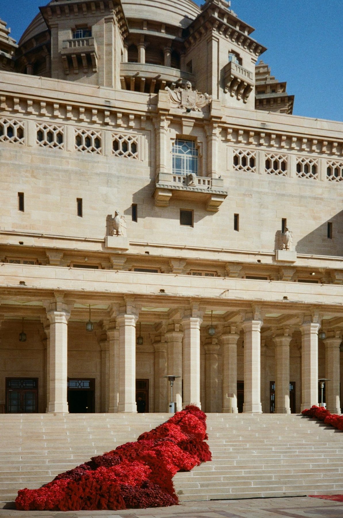 A cascade of red flowers spilling down the sandstone steps of Umaid Bhawan Palace