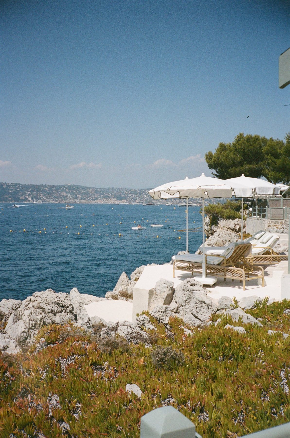 White umbrellas and loungers on a terrace above the blue bay