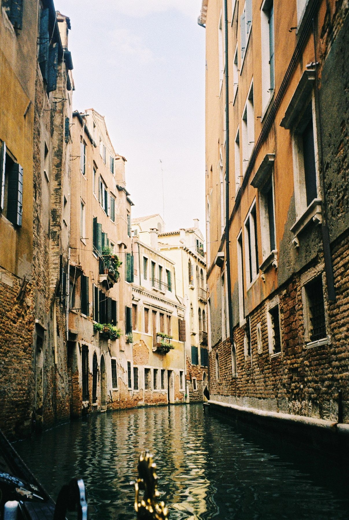 Ochre walls rising over a dark canal seen from the bow of a gondola