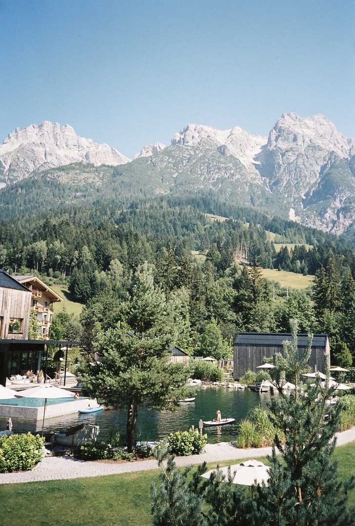 A resort pool and lawn below a wall of pale limestone peaks
