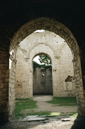 Looking through a round stone arch into a ruined chapel