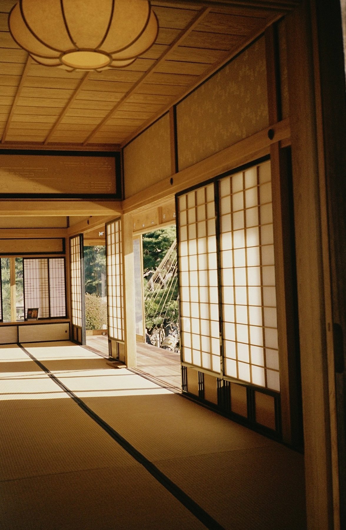 Low sun across tatami mats through open shoji screens, a paper lantern overhead