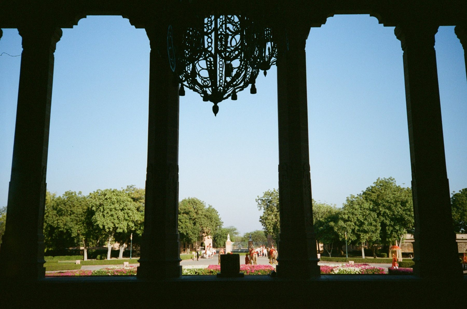 Palace arches framing a chandelier and the wedding procession on the lawn