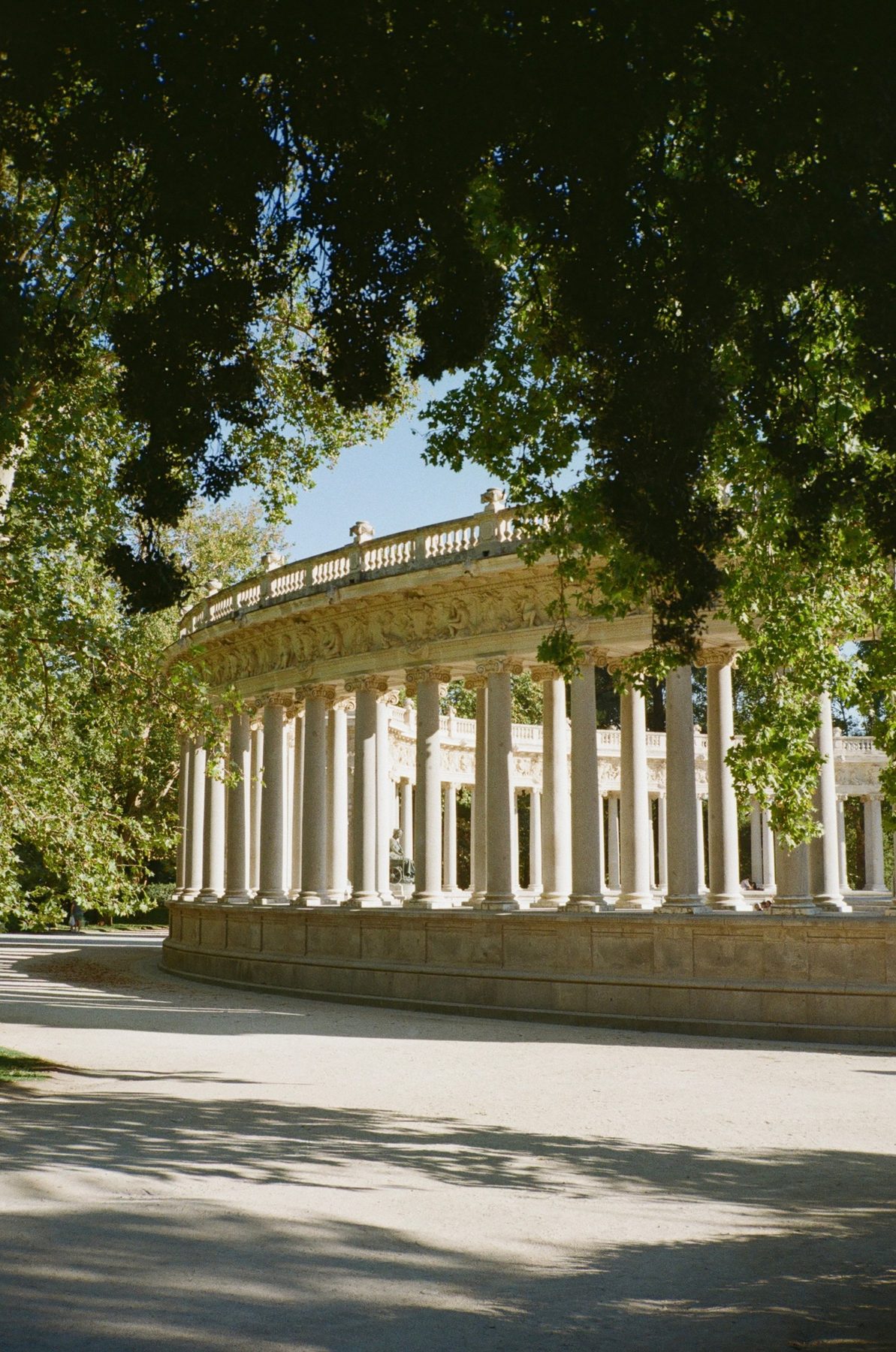 The curved colonnade in Retiro park, framed by dark leaves