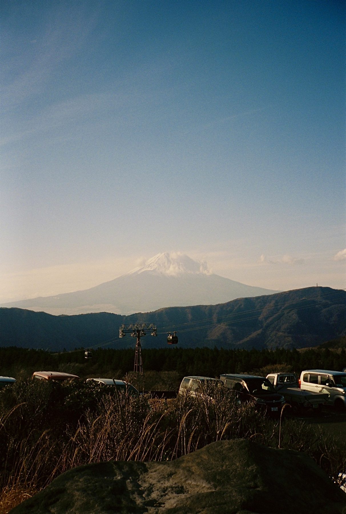 Mount Fuji rising beyond dark hills and a ropeway at dusk