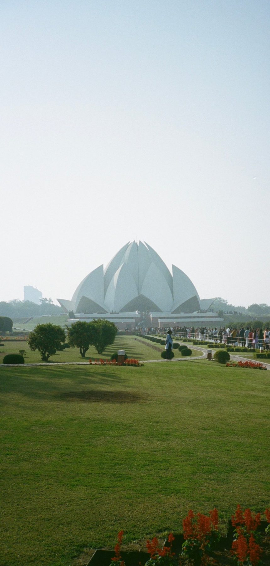 The white Lotus Temple rising beyond gardens and a long queue