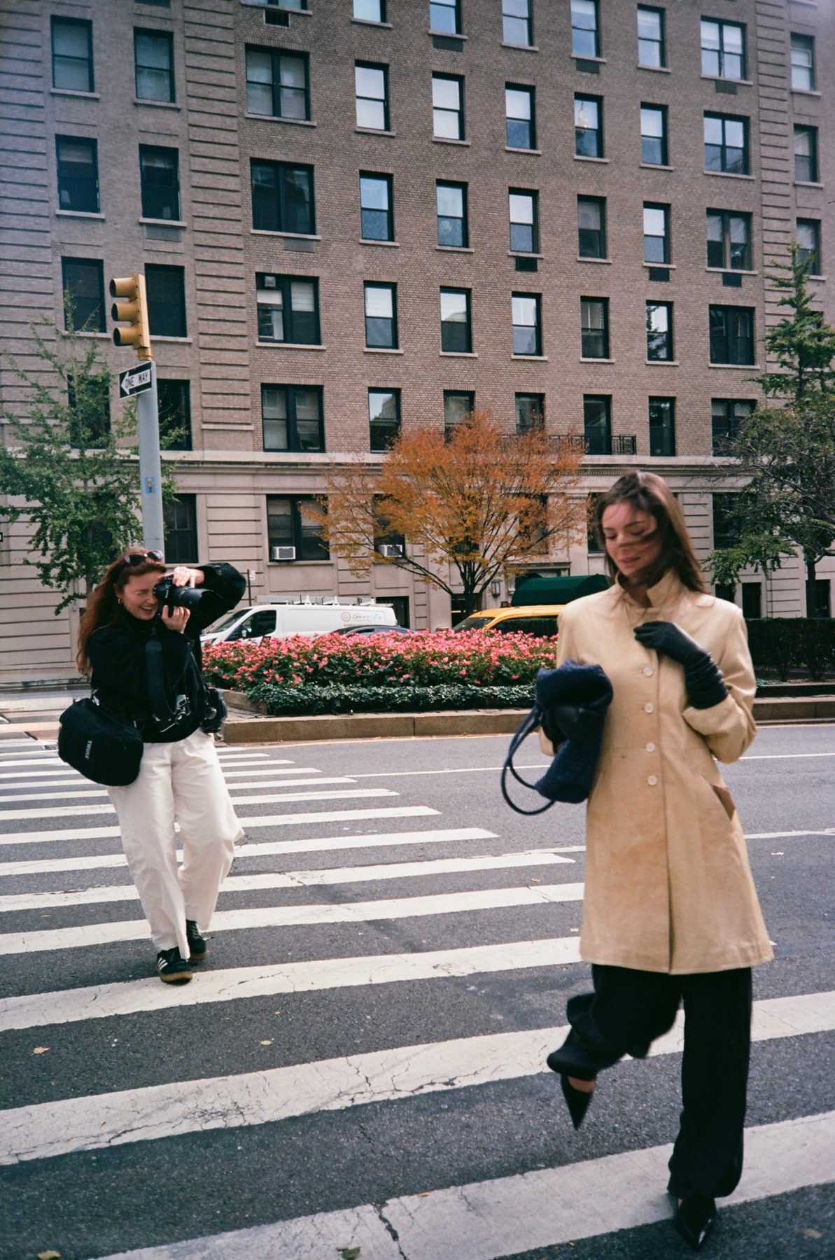 A model in a suede coat crossing Park Avenue, wind in her hair, the photographer laughing behind