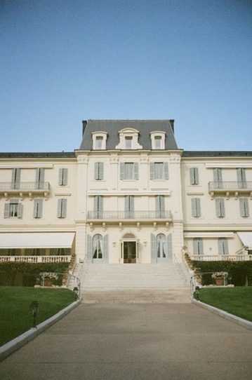 The cream facade of a grand hotel with pale blue shutters