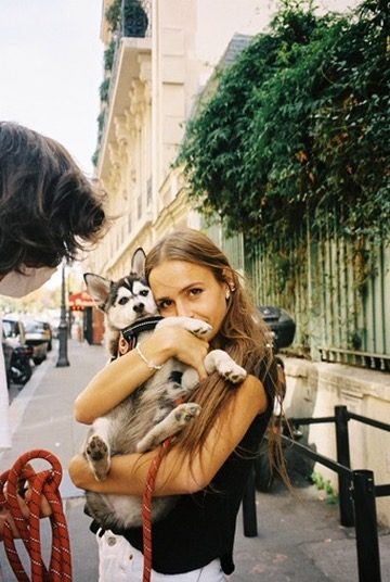 A woman hugging a husky puppy on a Paris street