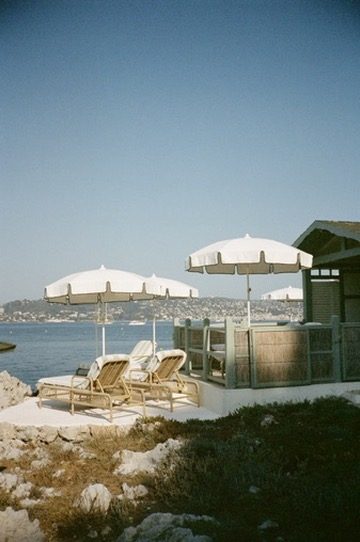 Two loungers under fringed umbrellas by a wooden cabana