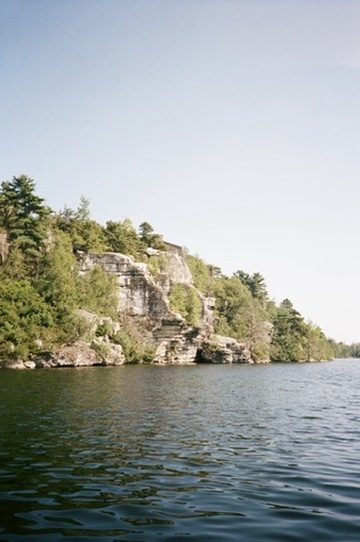 Pale cliffs and pines rising above dark lake water