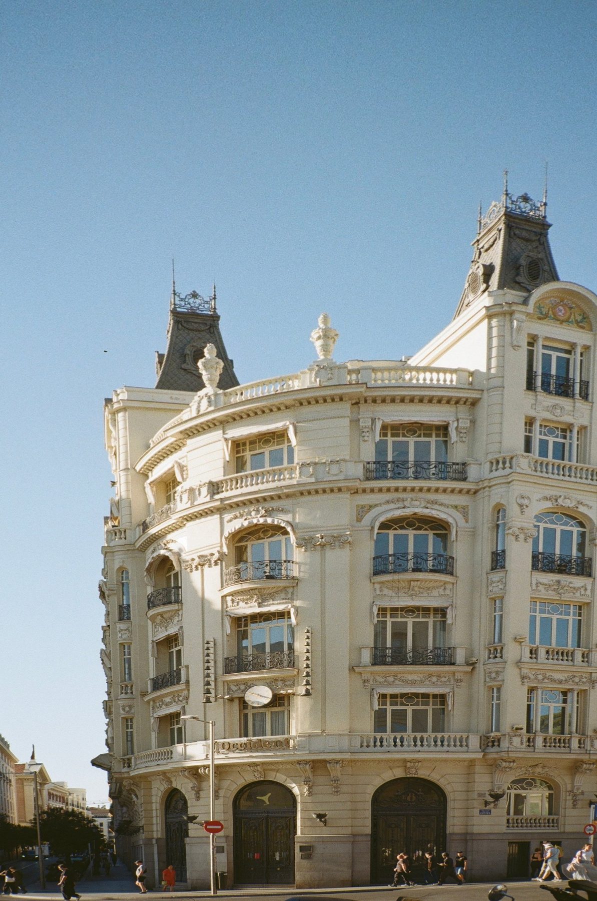 An ornate cream corner building with black turrets and iron balconies