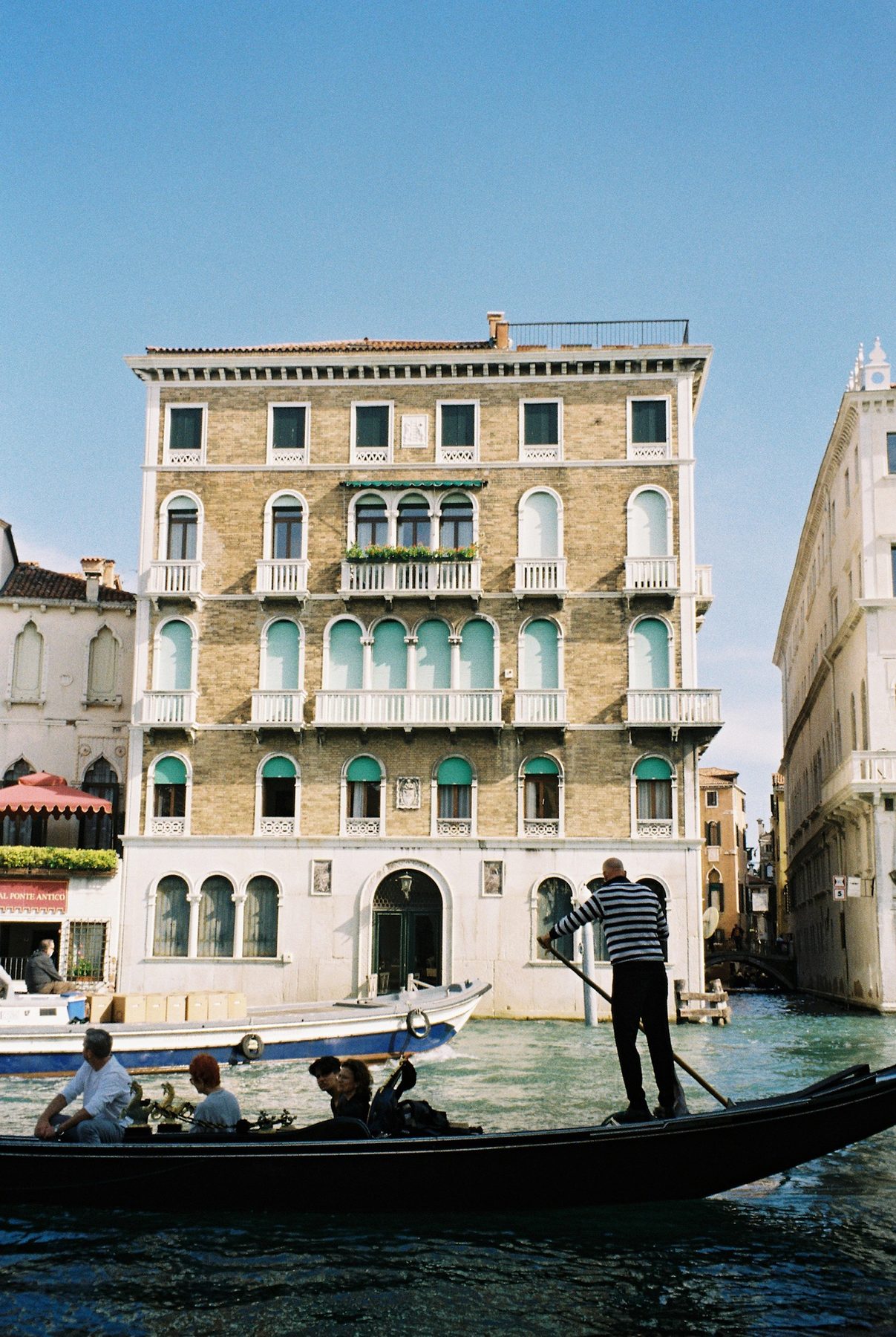 A gondola gliding past a palazzo with green shutters and white balconies