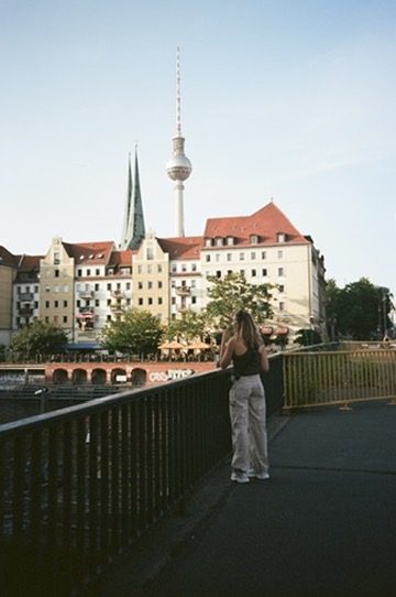A woman on a bridge looking toward the Berlin TV Tower