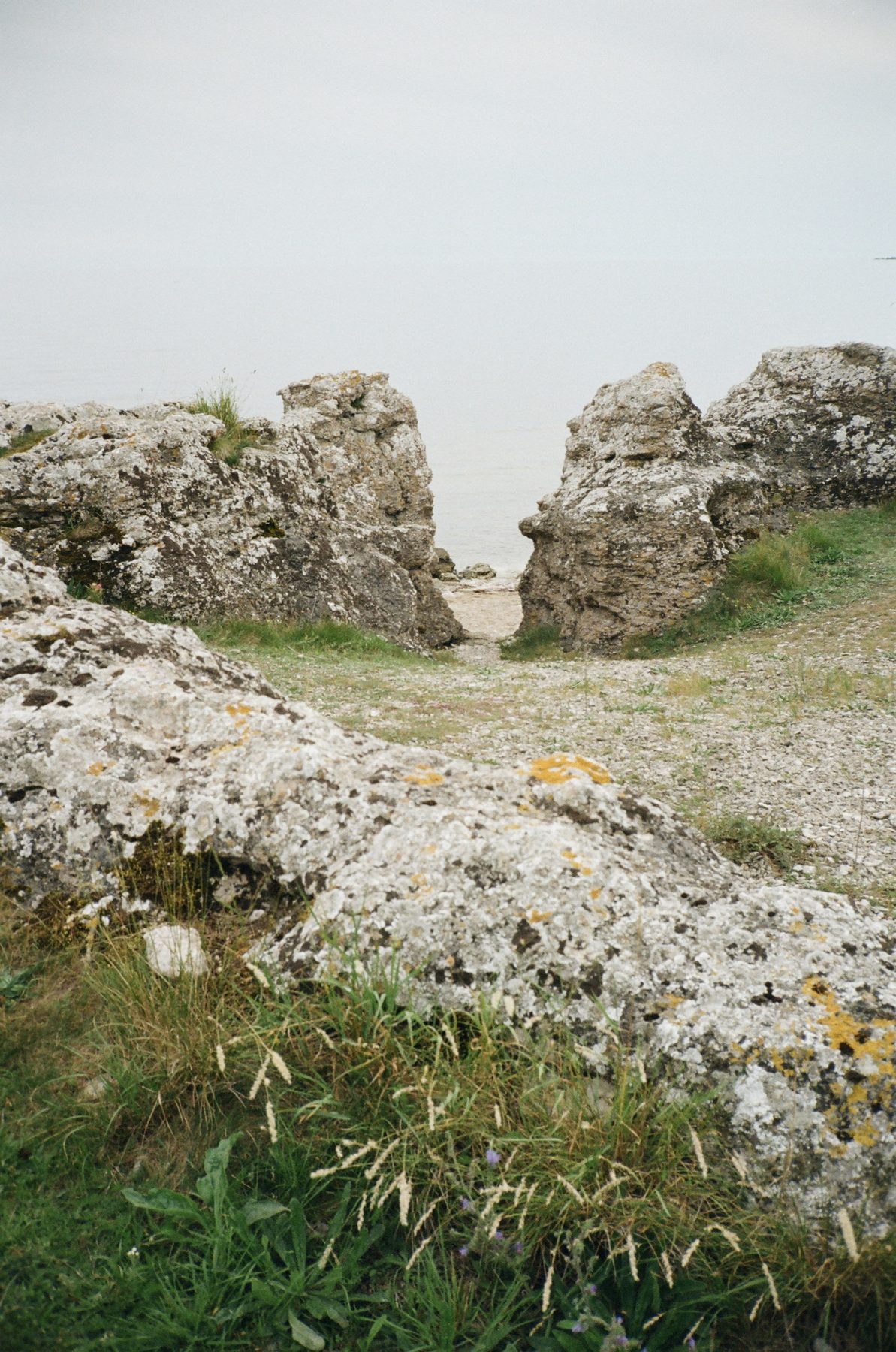 Lichen-covered limestone boulders framing a gap to the sea
