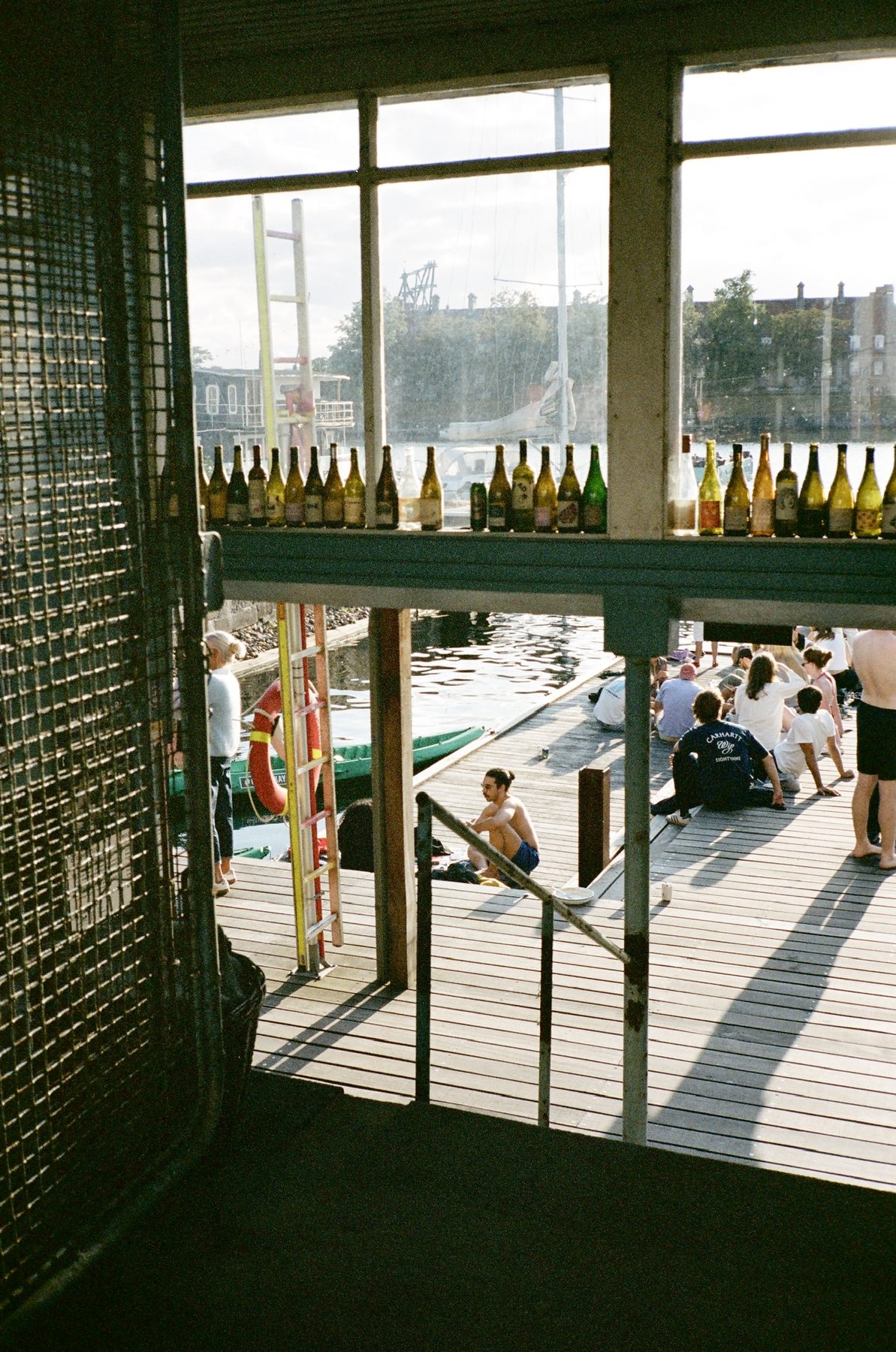 A harbor dock seen through a window lined with empty wine bottles