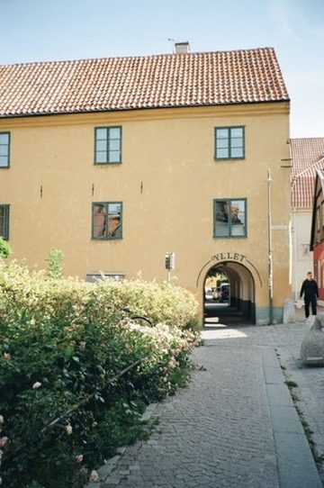 A yellow building with an arched passage on a Visby street