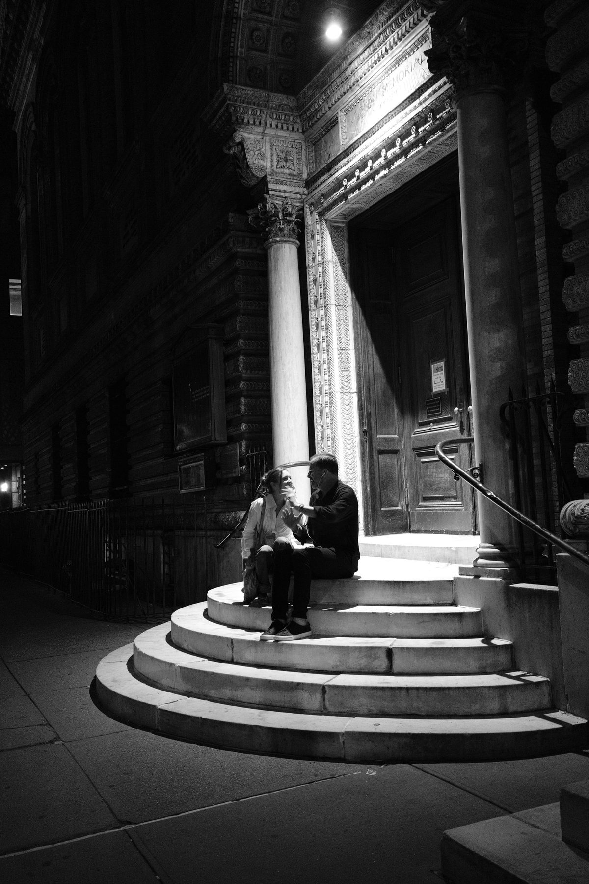 Wide view of the pair on the curved church steps below the carved columns and doorway