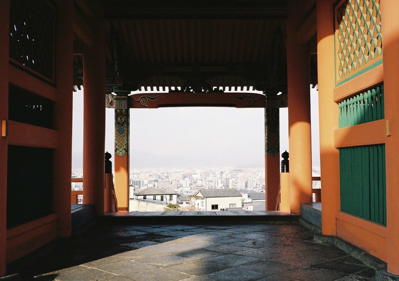 A vermilion temple gate framing the hazy city below