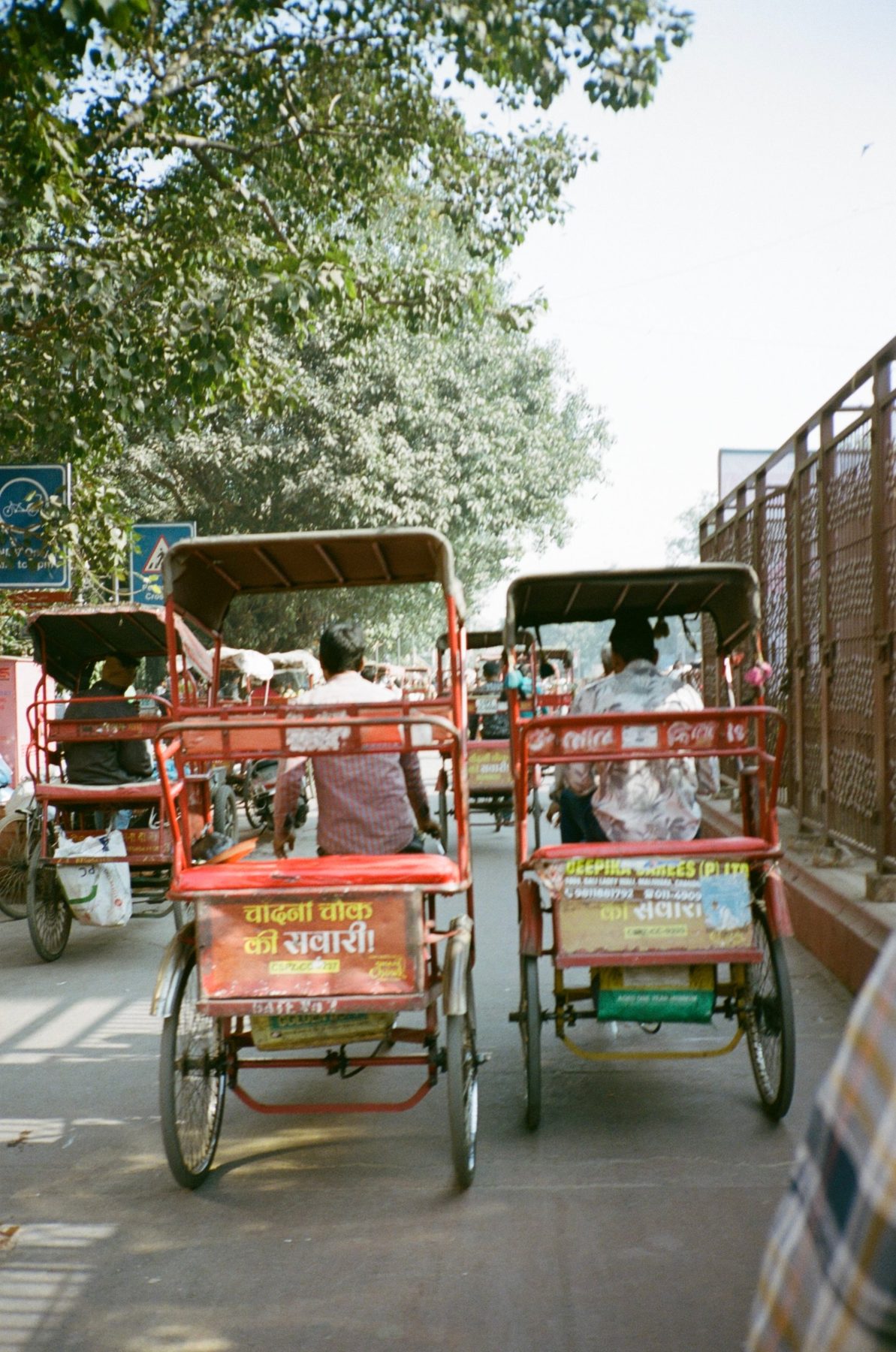 Two red cycle rickshaws side by side on a Chandni Chowk street