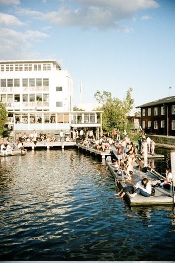 People on floating docks below a white building