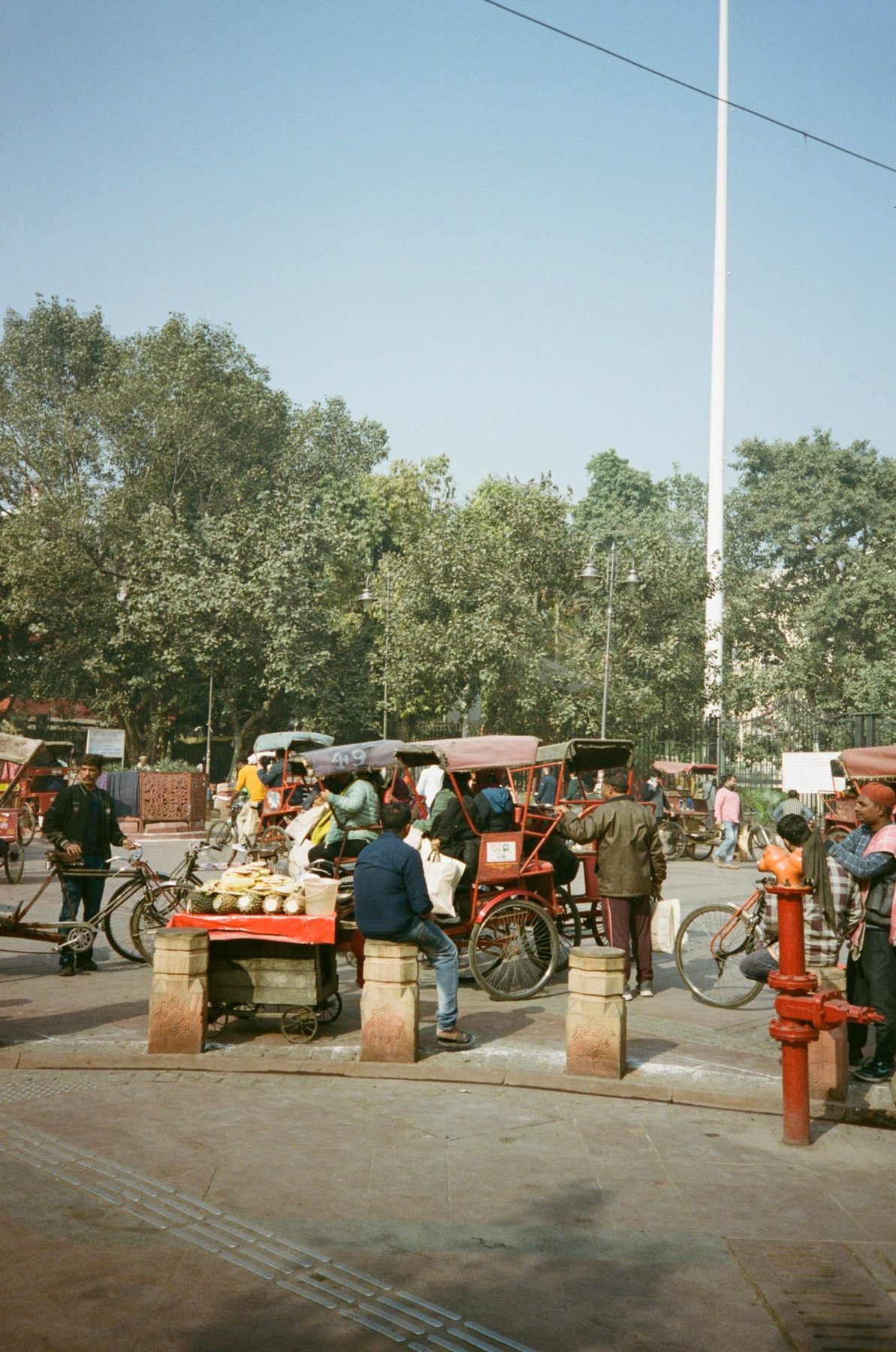 Rickshaws and a pineapple cart gathered at a busy square