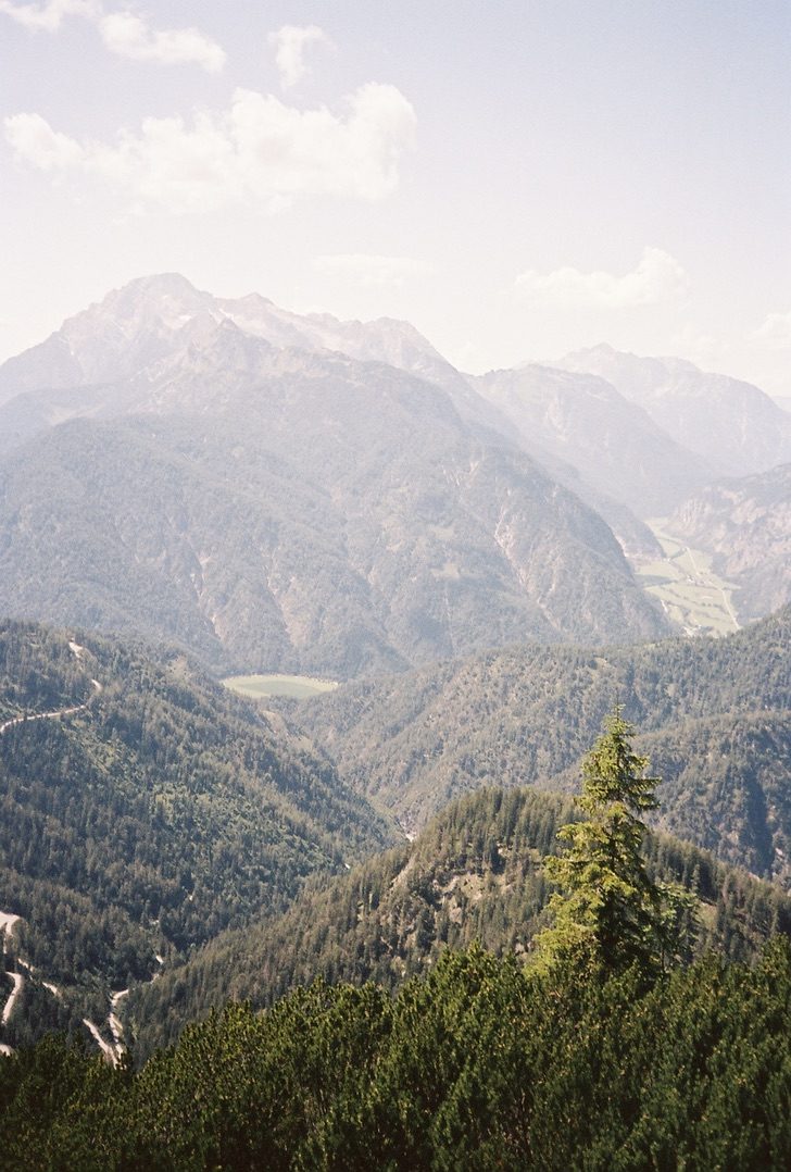 Hazy layered ridges above a valley, a single pine in front