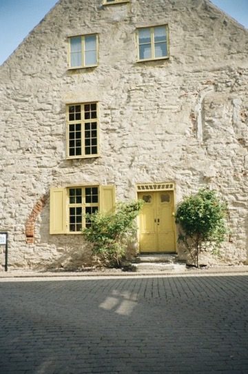 A stone house with a yellow double door on a cobbled street